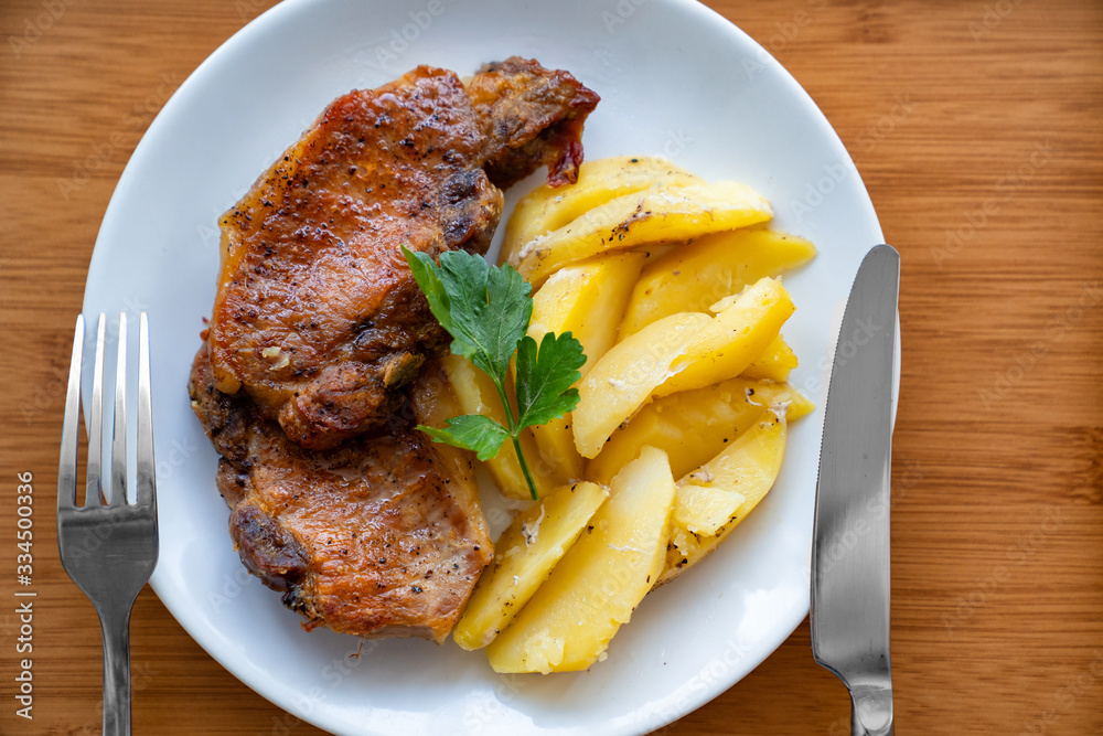 meat and potatoes on a white plate. wooden tray. 