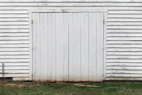 faded white wooden warehouse building doorway grass