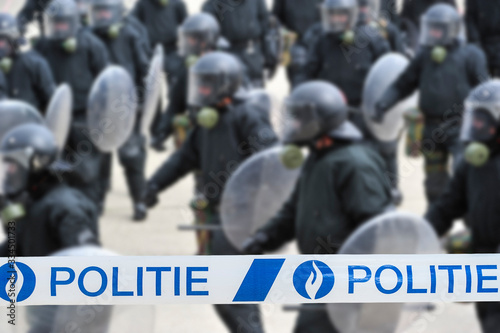 Politie / police tape in front of Belgian riot squad forming a protective barrier with riot shields in Belgium