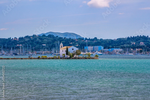 View of beautiful Gouvia Bay, ancient Ypapanti church – small white house on a pier, port marina, coast and mountains, covered with green trees. Summer landscape, Corfu Island, Greece.  photo