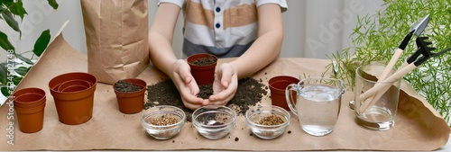  Planting seeds of micro greens. Child hands scooped up soil with palms folded together in a boat to fill capacities.