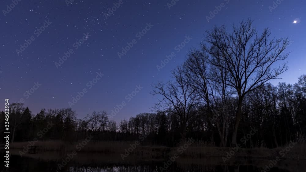 Day to night time lapse of the night sky in the forest with a lake in the forground Day to night time lapse of the night sky in the forest with a lake in the forground