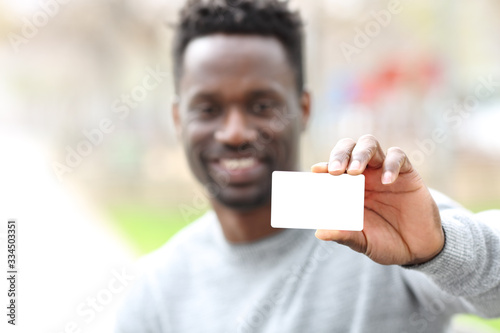 Happy black man showing blank credit card in the park
