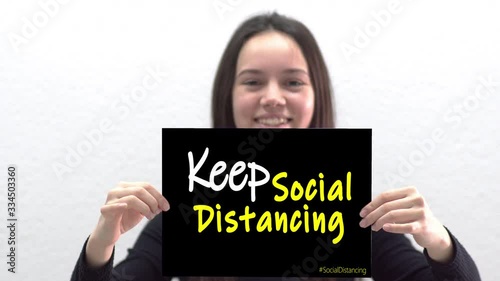 KEEP SOCIAL DISTANCING message concept. Teen hold ssign social distancing written on a blackboard. photo