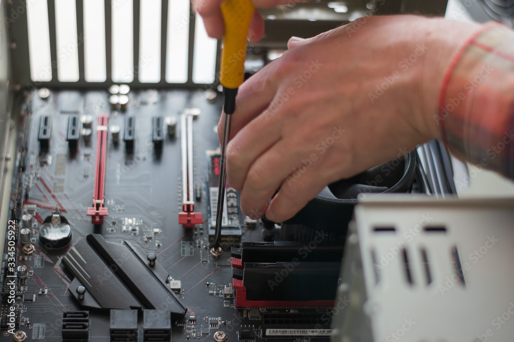 Installing a new motherboard in the system unit. Computer repair and upgrade. Close-up of the hands of a master repairing a computer. selective focus Installing a new motherboard in the system unit. Computer repair and upgrade. Close-up of the hands of a master repairing a computer. selective focus