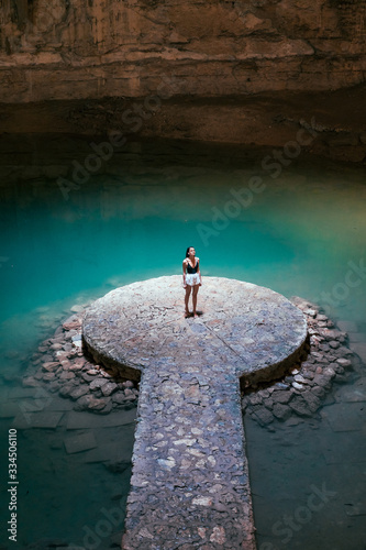 Girl in a cave with a blue cenote lake on the Yucatan