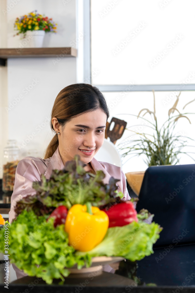 Beautiful woman smiling search how to cooking salad from internet by computer in kitchen. Beautiful woman smiling search how to cooking salad from internet by computer in kitchen.