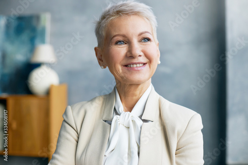 Job, office work and occupation concept. Beautiful confident middle aged female boss in formal wear smiling, rejoicing after good business negotiations with partners, going to make profitable deal photo