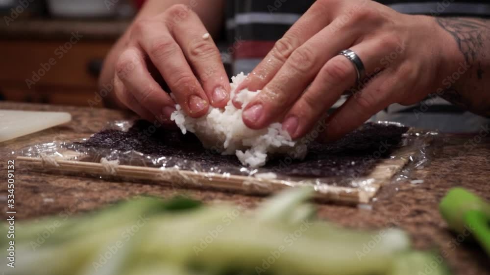 Man spreading rice onto seaweed making sushi slow motion close up