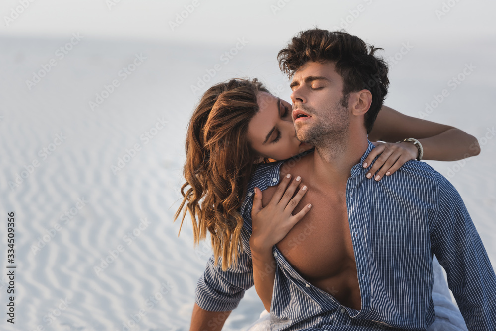 Fototapeta premium passionate young woman touching boyfriend torso on beach
