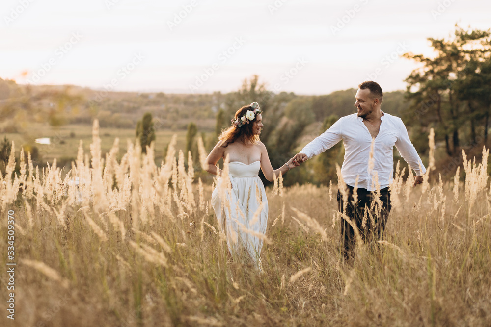 Beautiful woman in wreath together with her courageous husband, spends time together in nature at sunset. Beautiful woman in wreath together with her courageous husband, spends time together in nature at sunset.