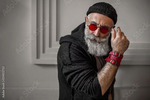 Brutal man indoors in red eyeglasses. Stylish old man.