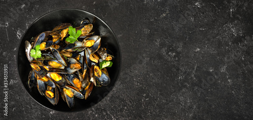 Top view of freshly cooked mussels in a black plate on dark background photo