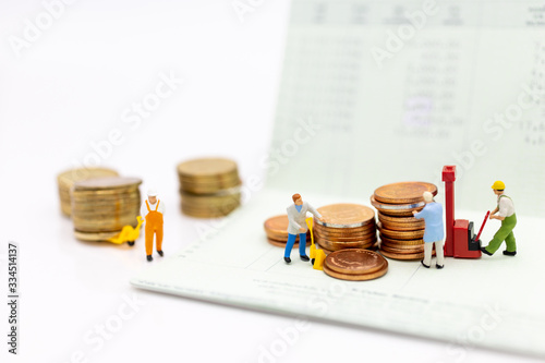 Miniature people : Workers and a pile of coins on a book bank for extend the progress, image use for stable growth growing progress