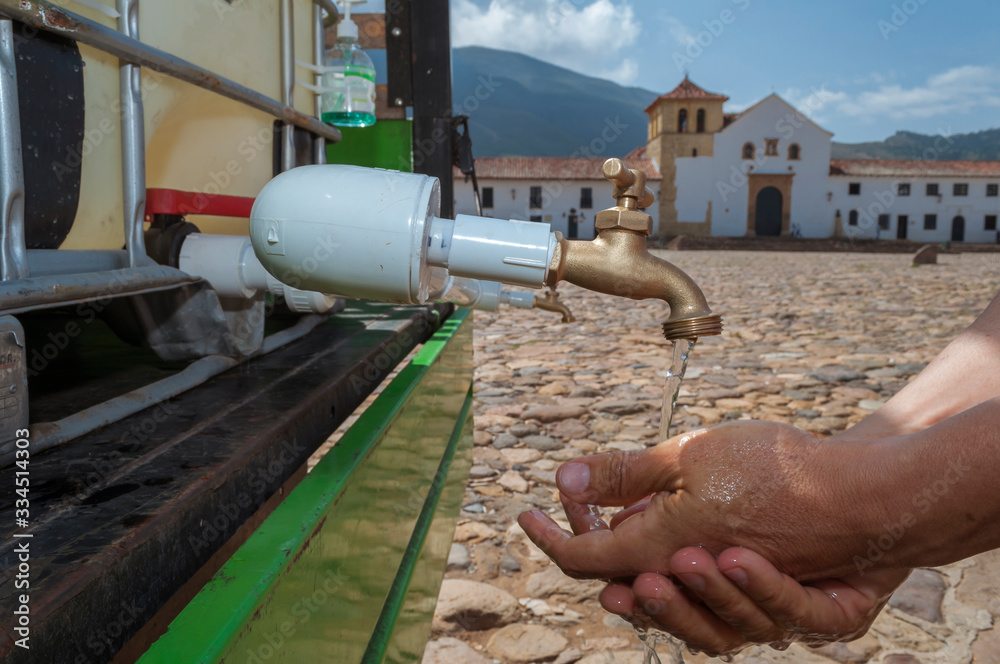 Sink in the main square of Villa de Leyva Boyacá Colombia is used by a man with the aim of preventing viral diseases such as the covid19 coronavirus Sink in the main square of Villa de Leyva Boyacá Colombia is used by a man with the aim of preventing viral diseases such as the covid19 coronavirus