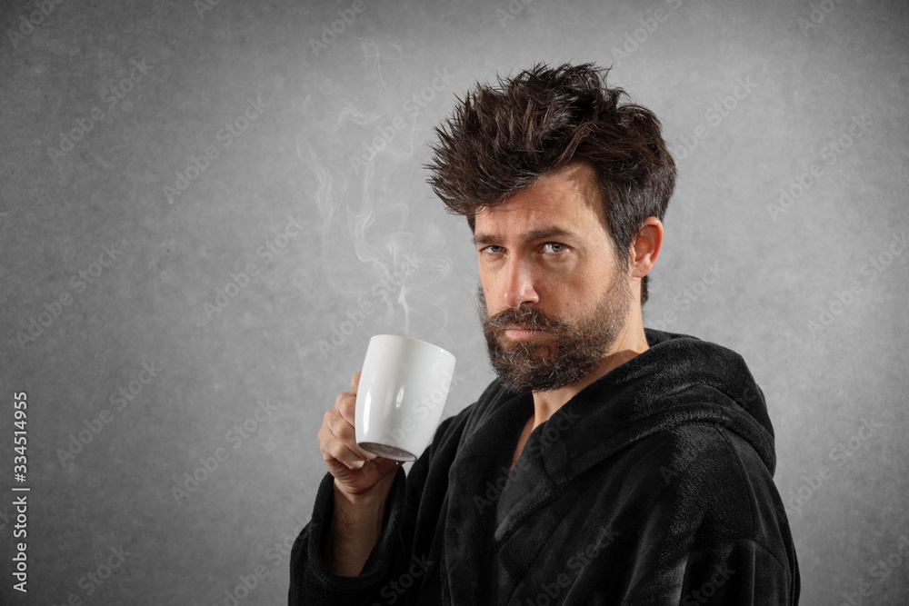 Man in bathrobe with funny hair cup of coffee isolated background Man in bathrobe with funny hair cup of coffee isolated background