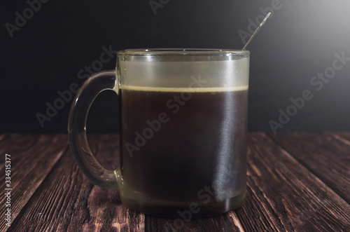 cup of tasty coffee and a spoon on a wooden table. Image is tinted. Morning Coffee. Dramatic image.