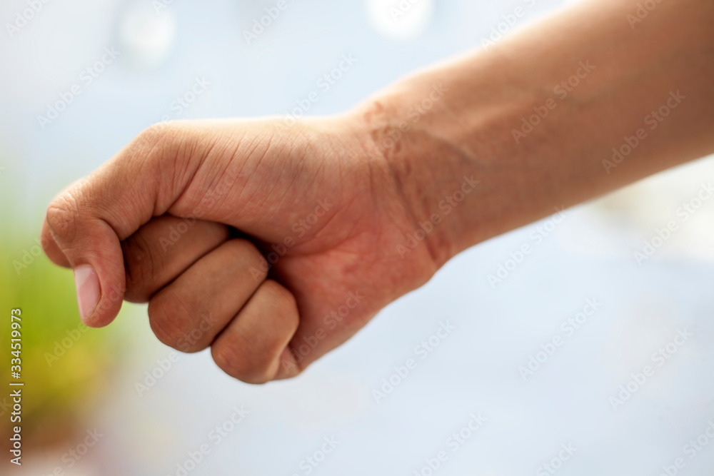 Shot of male hand with the impact of chain tied on his wrist. Shot of human hand with chain impact with blurred background.