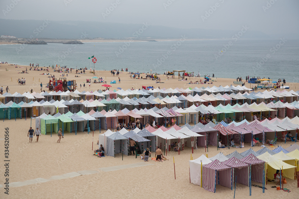 Nazaré, Portugal: Bunte gestreifte Badezelte am Strand 