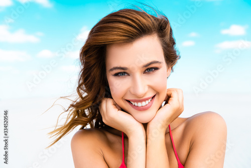 smiling beautiful sexy girl in swimsuit on beach with blue sky and clouds