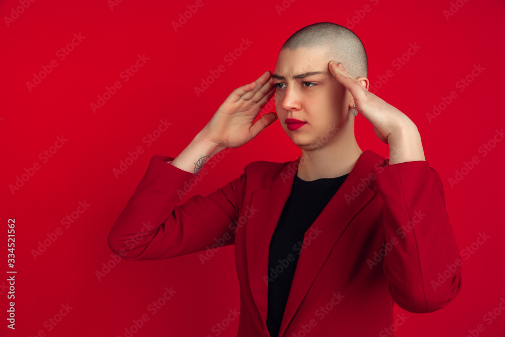 Headache, problem. Portrait of young caucasian bald woman isolated on red studio background. Beautiful female model in jacket. Human emotions, facial expression, sales, ad concept. Freaky culture. Headache, problem. Portrait of young caucasian bald woman isolated on red studio background. Beautiful female model in jacket. Human emotions, facial expression, sales, ad concept. Freaky culture.