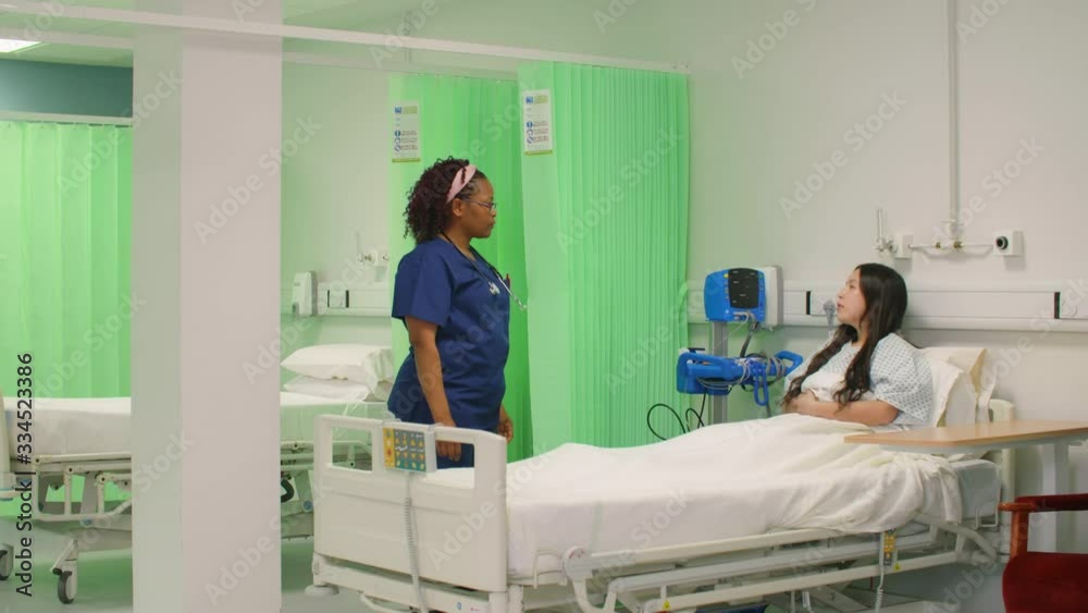 Female Nurse Chatting to Patient in Hospital Bed Female Nurse Chatting to Patient in Hospital Bed