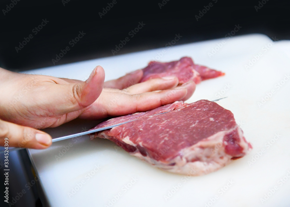 chef at work, sliced pork on cutting board for cooking, cutting pork with knife on a plastic board