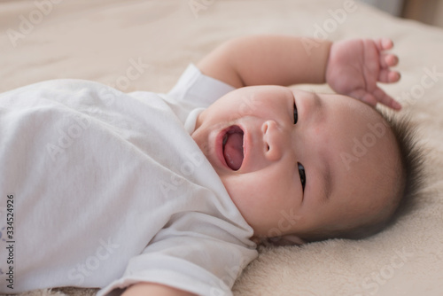newborn child relaxing in bed. adorable baby boy in white sunny bedroom. nursery for young children. textile and bedding for kids. family morning at home. six month. childhood and baby care concept.