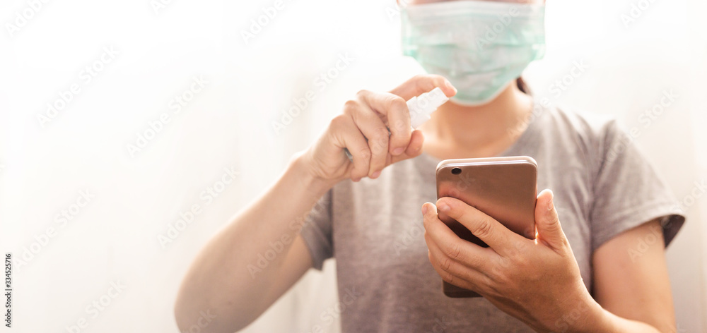 Women wearing protective masks Covid -19 and Hold an alcohol spray with mobile phone. Women wearing protective masks Covid -19 and Hold an alcohol spray with mobile phone.