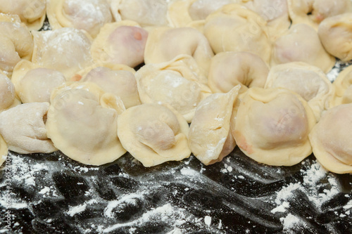 Dumplings, cooked at home, lie on a plate, sprinkled with flour.