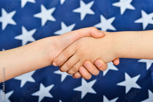 Friendly handshake of people on the background of the American flag.