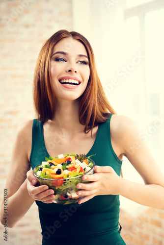 Portrait of happy smiling attractive woman with vegetarian vegetable salad, indoors or at home. Beauty and dieting concept. Weight lossing, by healthy eating.