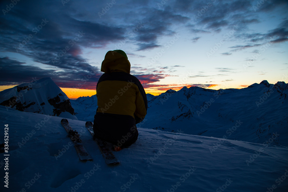 Men silhouette in the darkness of the winter. Sunset in the Swiss Alps.
