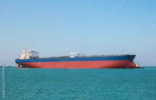 big Oil Tanker ship sailing in the sea with tug boat assistance forward, Oil and gas industry liquefied natural gas tanker LPG in the sea on blue sky background.
