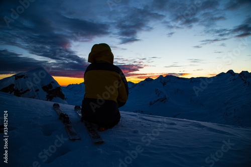 Men silhouette in the darkness of the winter. Sunset in the Swiss Alps.