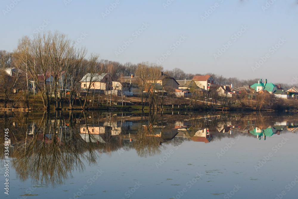 Spring morning on the lake, reflection of houses in the water, silence and calm of dawn