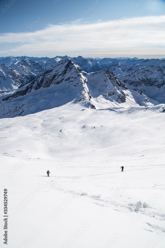 Mens on a ski tour in the back country of the Swiss Alps in fresh powder snow