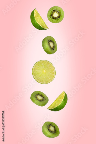 Falling limes and kiwi isolated on a pink background with clipping path. Flying fruits