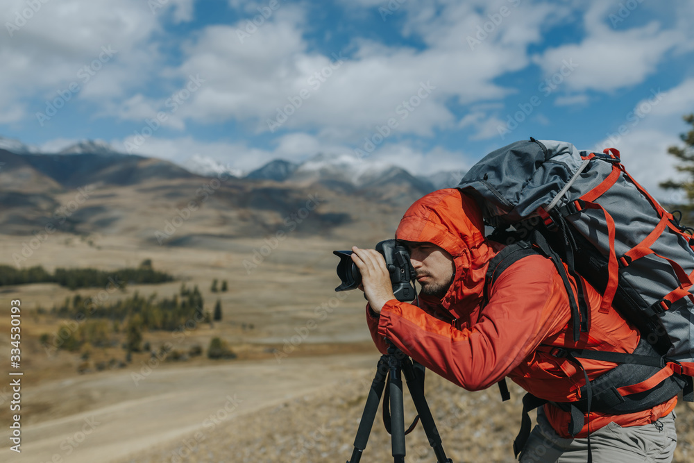 Travel photographer man taking nature video of mountain landscape. Hiker tourist professional videographer on adventure vacation shooting slr camera on tripod.