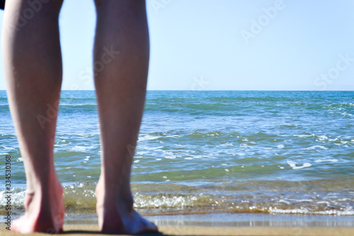 blurred legs of a tourist in the foreground against the background of the sea