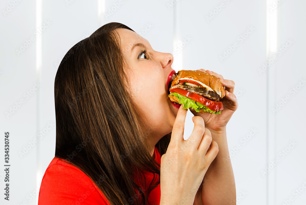 Young fat woman holds hamburger, smiles with opened mouth Young fat woman holds hamburger, smiles with opened mouth