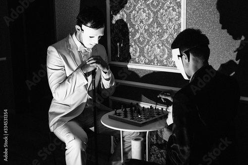 two masked guys are playing chess, black and white photo