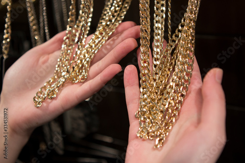 hands hold a lot of gold-plated chains from the store counter, the buyer chooses jewelry