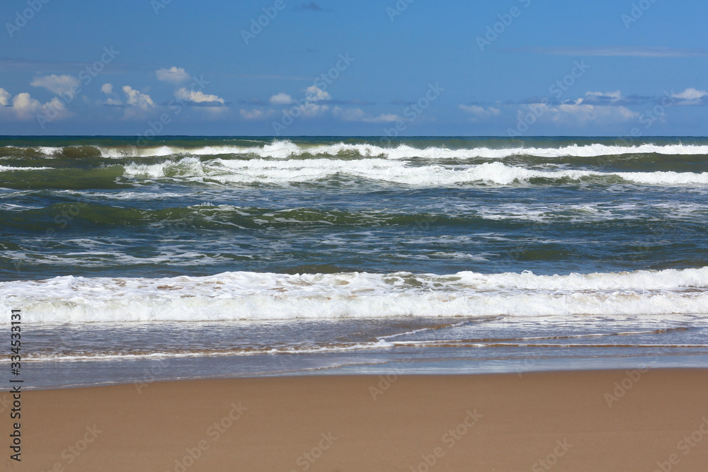 Cumulus clouds and surf. Yellow sand. Calm before the storm.