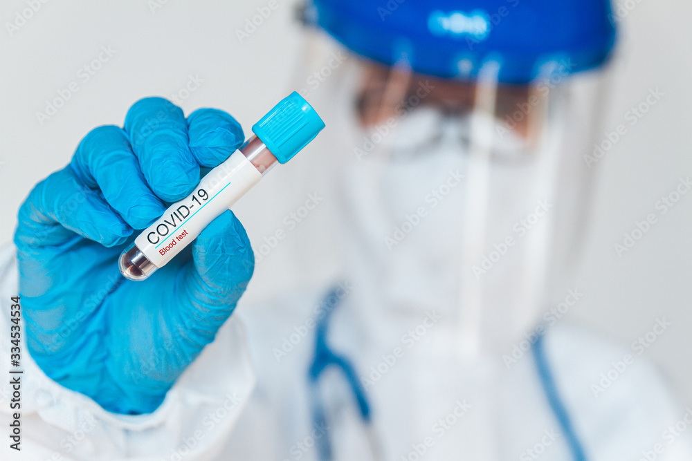 Female doctor or nurse in protective suit holding a positive blo Female doctor or nurse in protective suit holding a positive blo