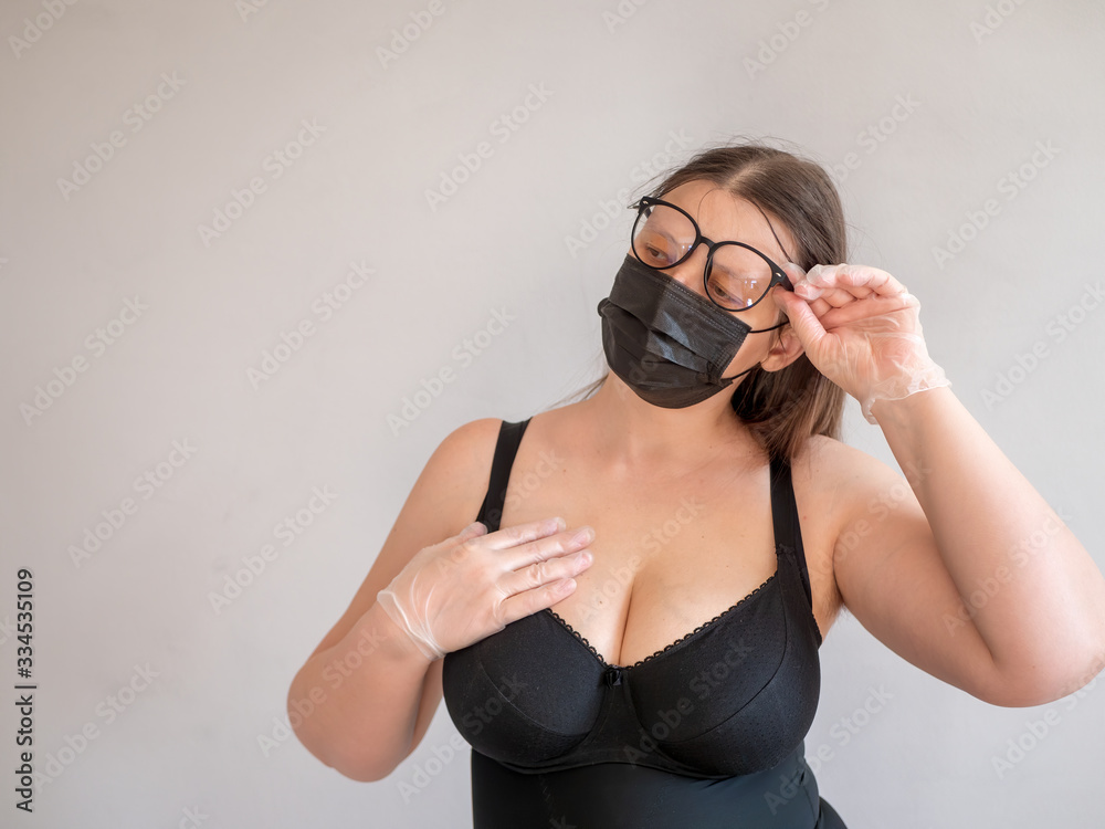 Adult woman in tightening corset in black protective mask and big glasses posing in front of camera. concept of protecting medical personnel from infections and viruses