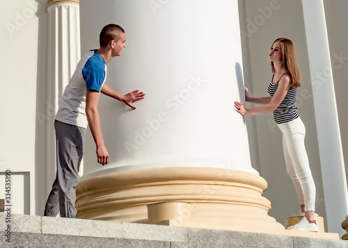 Yuna teenage couple walking around the historical architectural columns in a city park on a hot day. Love concept. Catch-up game photo