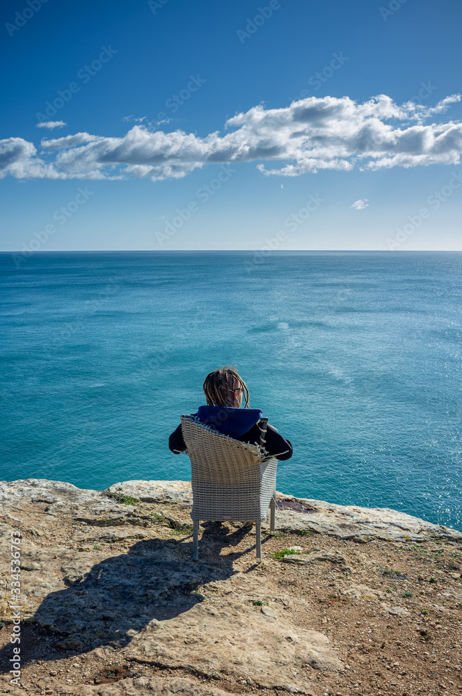 Man sitting on a rattan chair, watching blue ocean and enjoying life. Vacation lifestyle concept. Remote work concept. Portugal, Algarve, Praia do Carvoeiro. Man sitting on a rattan chair, watching blue ocean and enjoying life. Vacation lifestyle concept. Remote work concept. Portugal, Algarve, Praia do Carvoeiro.