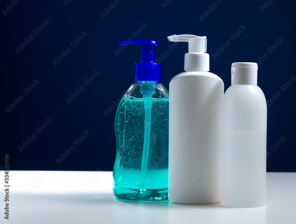 Plastic white antiseptic bottle with a dispenser on a blue background. The white package is on a white table. Plastic white antiseptic bottle with a dispenser on a blue background. The white package is on a white table.