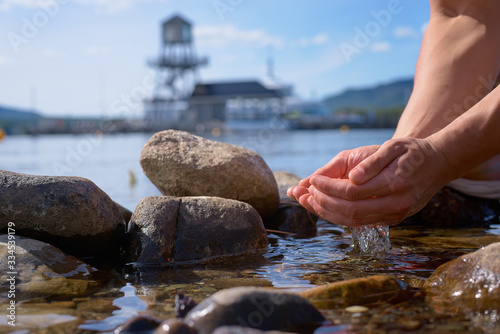 Male hands pick up clean water from Memphremagog lake, Province of Quebec, Canada